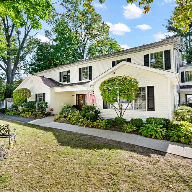 A two-story residential house with well-maintained landscaping and a green lawn.