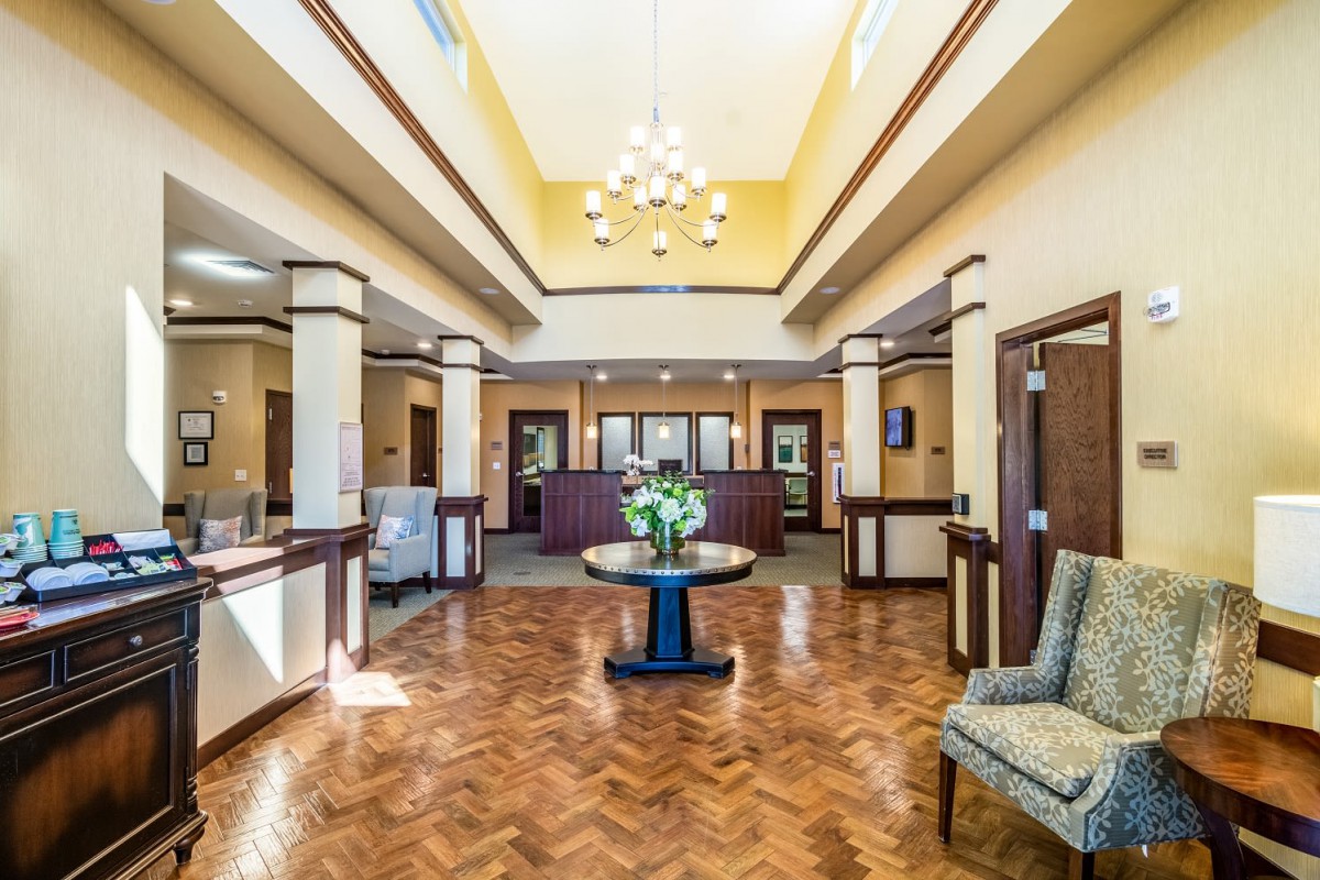 A spacious and well-lit lobby with a reception desk, decorative plants, and comfortable seating.