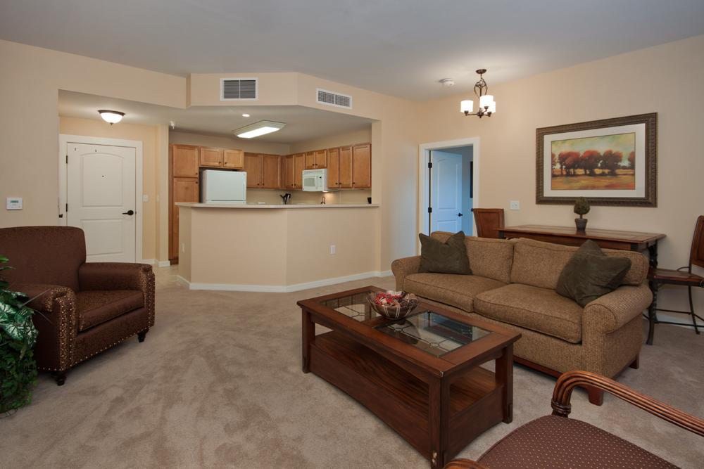 A cozy living room with a sofa, coffee table, and an open view into the kitchen.