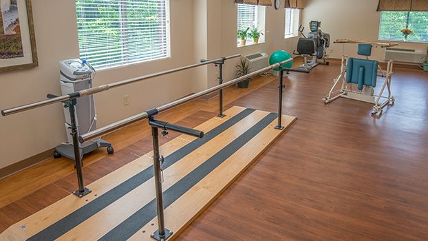A rehabilitation room equipped with parallel bars and exercise equipment for physical therapy.