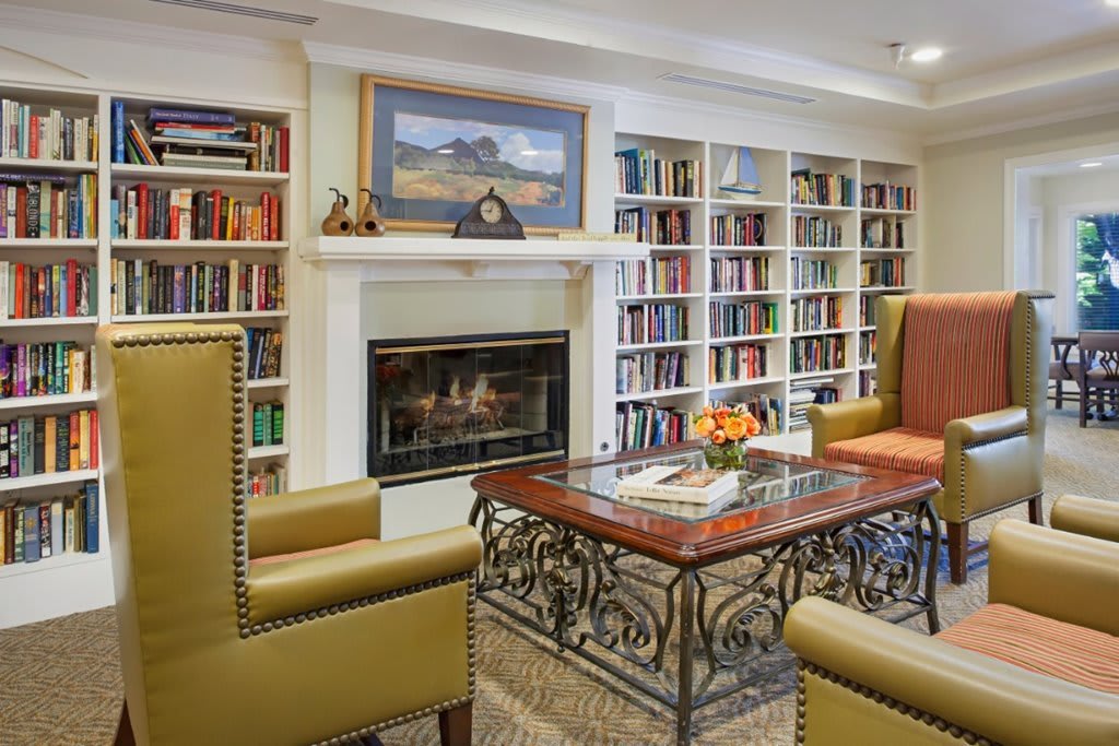 A cozy library room with bookshelves, a fireplace, and comfortable seating.