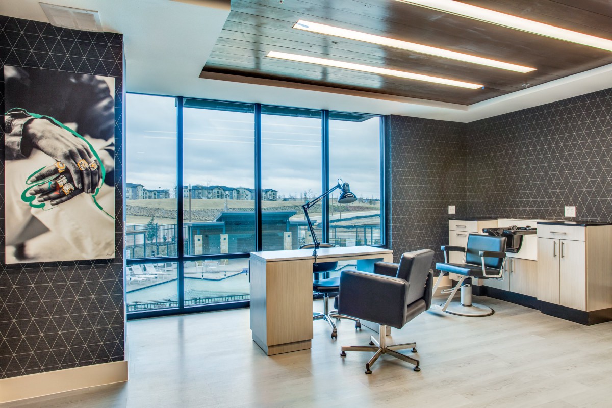 A modern office space with large windows offering a city view, featuring sleek furniture and a stylish design.