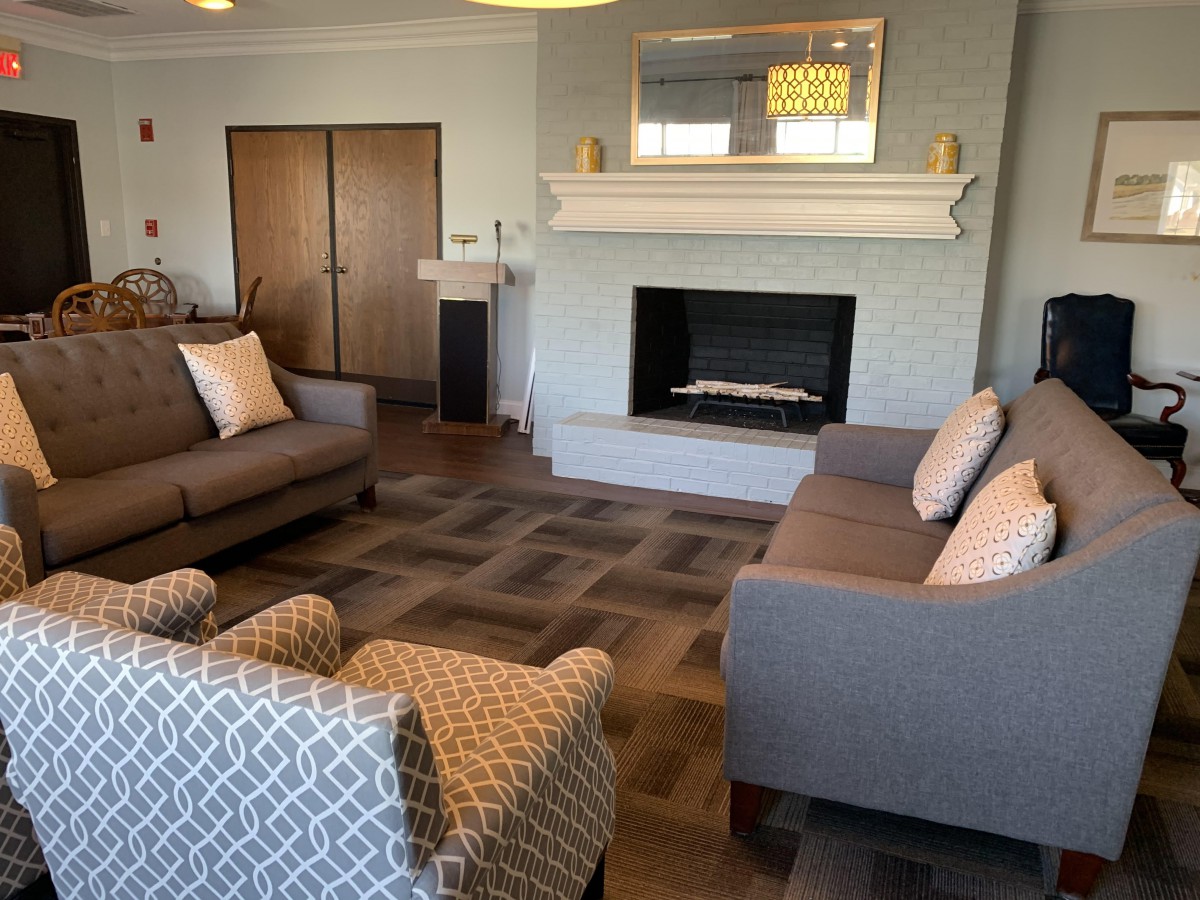 A cozy living room with a modern fireplace, sofas, and an armchair.