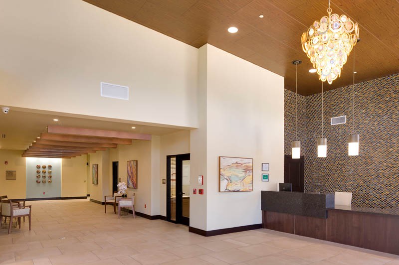 A modern lobby area featuring a reception desk, chandelier, and artwork on the walls.