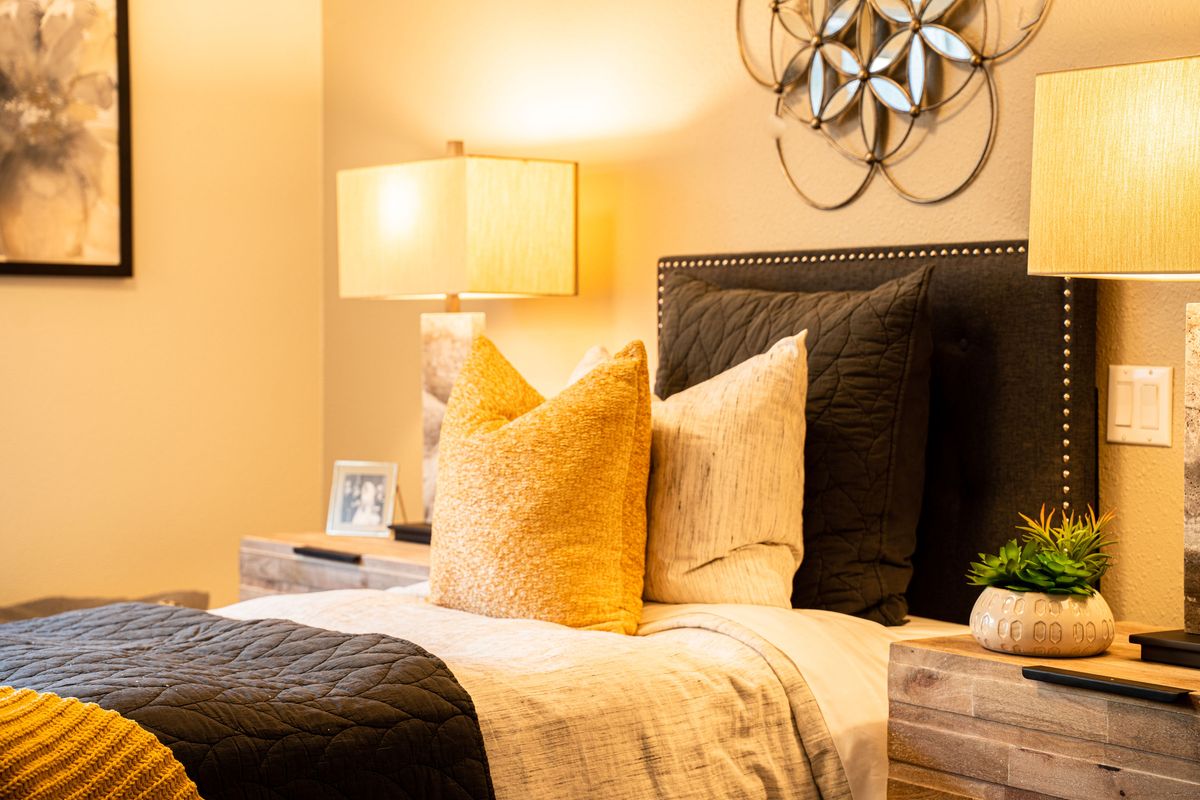 A cozy bedroom setting with stylish decor, featuring a bedside lamp and plush pillows.