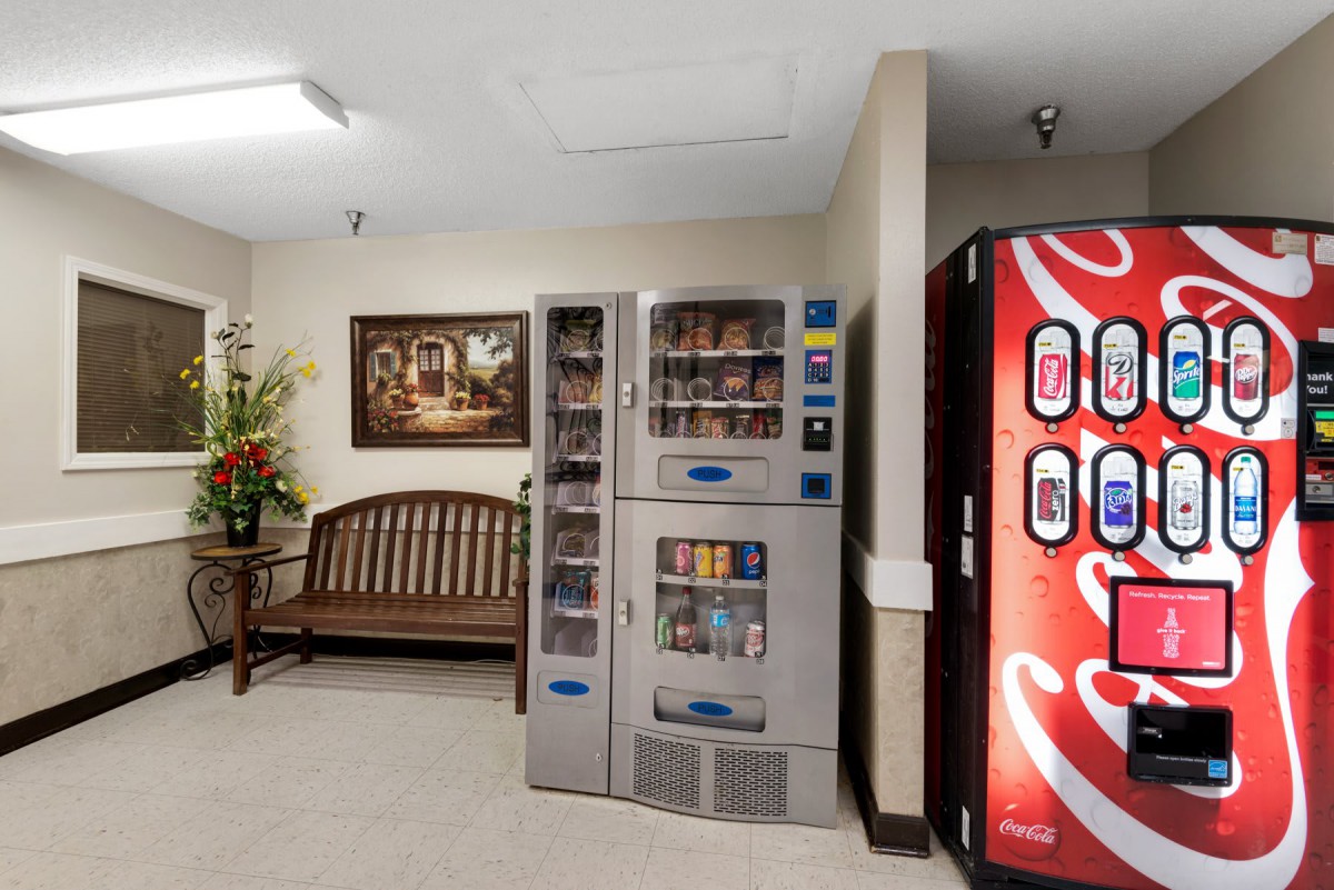 A cozy waiting area featuring vending machines, a wooden bench, and decorative elements.