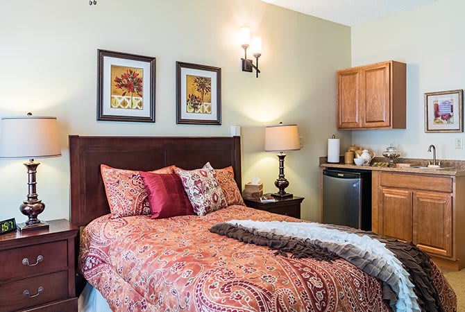 A cozy bedroom with patterned bedding, wall art, and warm lighting.
