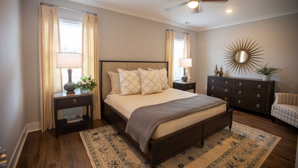 A cozy bedroom with a wooden bed frame, neutral bedding, and stylish decor.