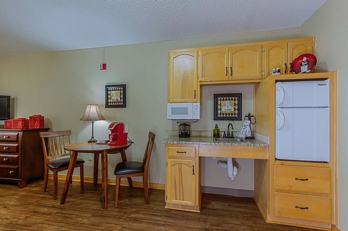 Cozy apartment kitchenette with wooden cabinetry and a small dining area.