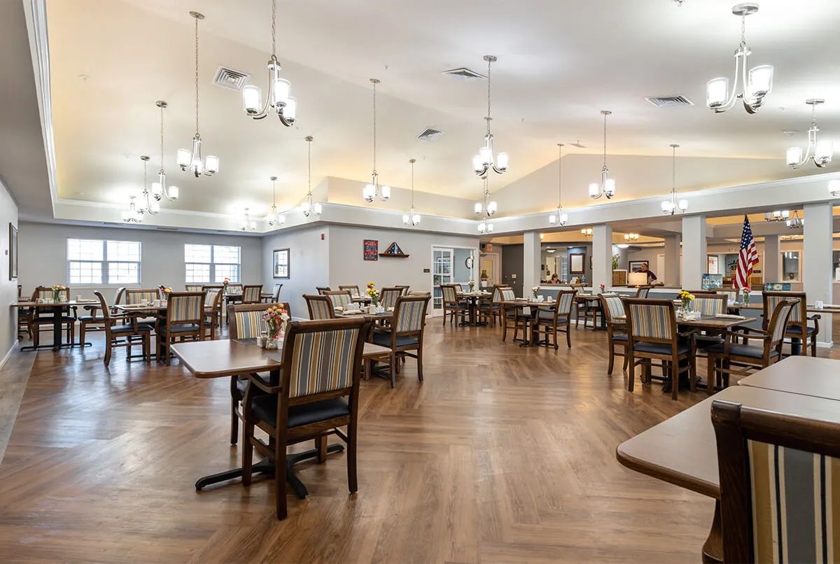 A spacious dining area with neatly arranged tables and chairs under elegant lighting.
