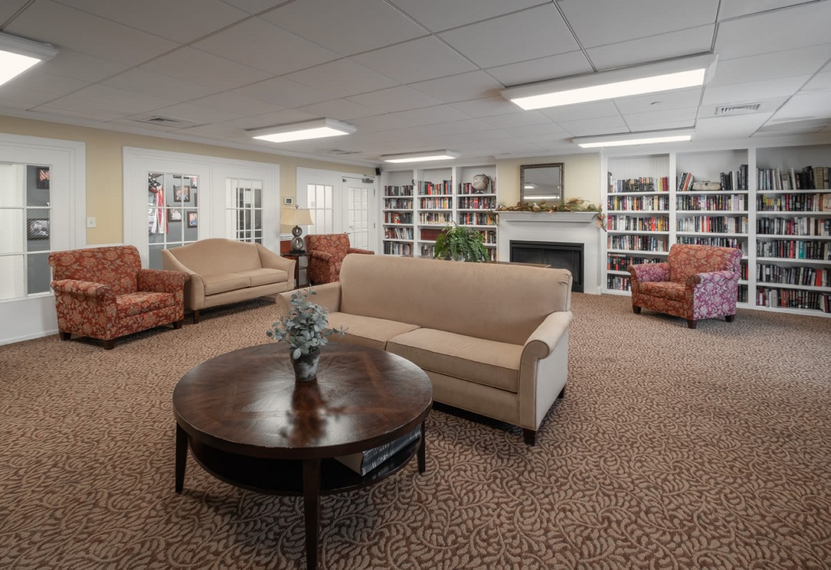 A cozy living room with sofas, armchairs, a coffee table, bookshelves, and a fireplace.
