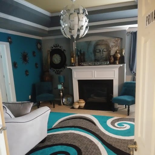 A stylish living room featuring a teal and white color scheme with a decorative rug and a fireplace.