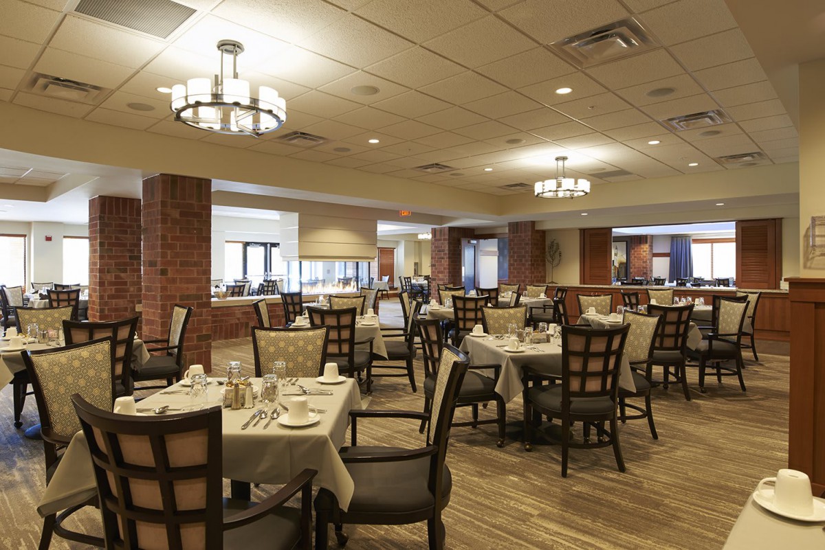 Empty restaurant dining room with neatly set tables and warm lighting.