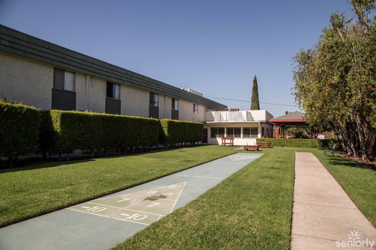 A residential building with a well-maintained lawn and shuffleboard court.