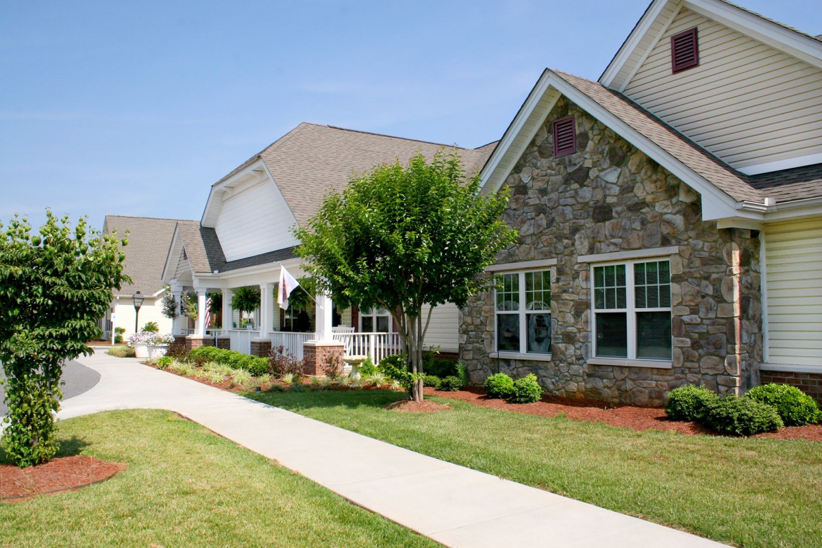 A charming residential house with a well-maintained front yard and stone exterior.