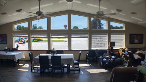 A spacious and well-lit indoor area featuring large windows, a dining table, and comfortable seating.
