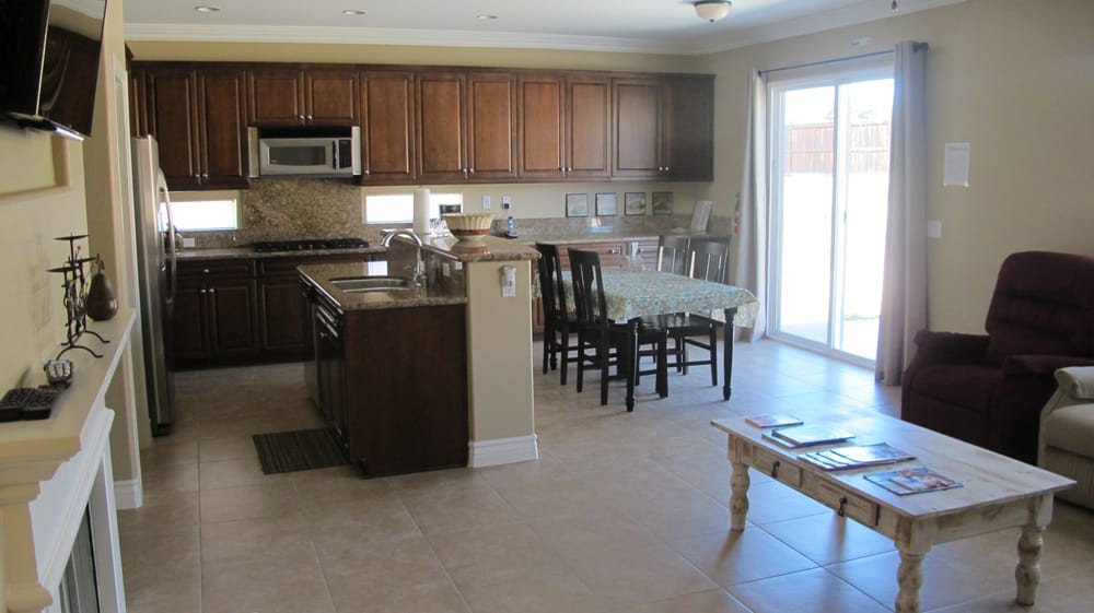 A modern kitchen and dining area featuring wooden cabinets, a central island, and a sliding glass door.