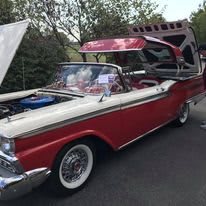 A vintage red and white convertible displayed at a car show.