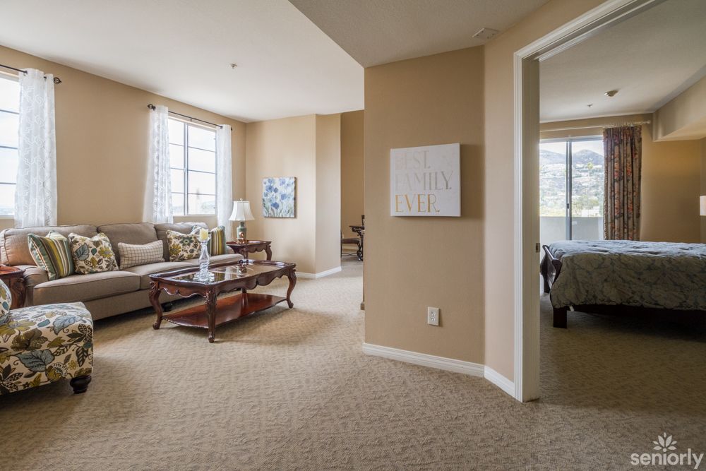A cozy living room with a sofa, coffee table, and ample natural light streaming through the windows.