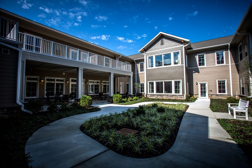A modern residential building with well-maintained landscaping under a clear blue sky.