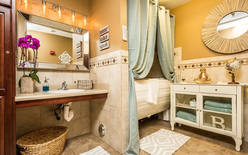 Elegant bathroom with a cozy and warm design featuring a vanity, decorative tiles, and soft curtains.