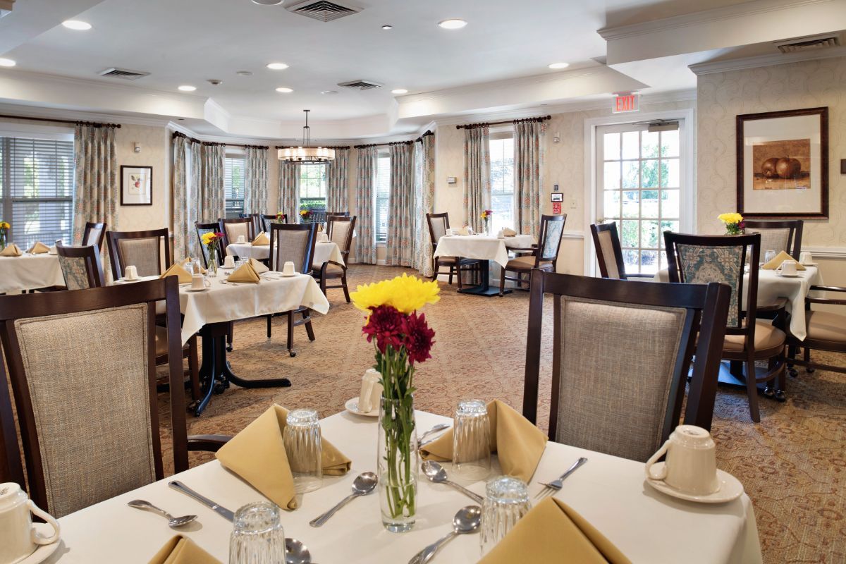 Elegantly set dining room with neatly arranged tables and a floral centerpiece.