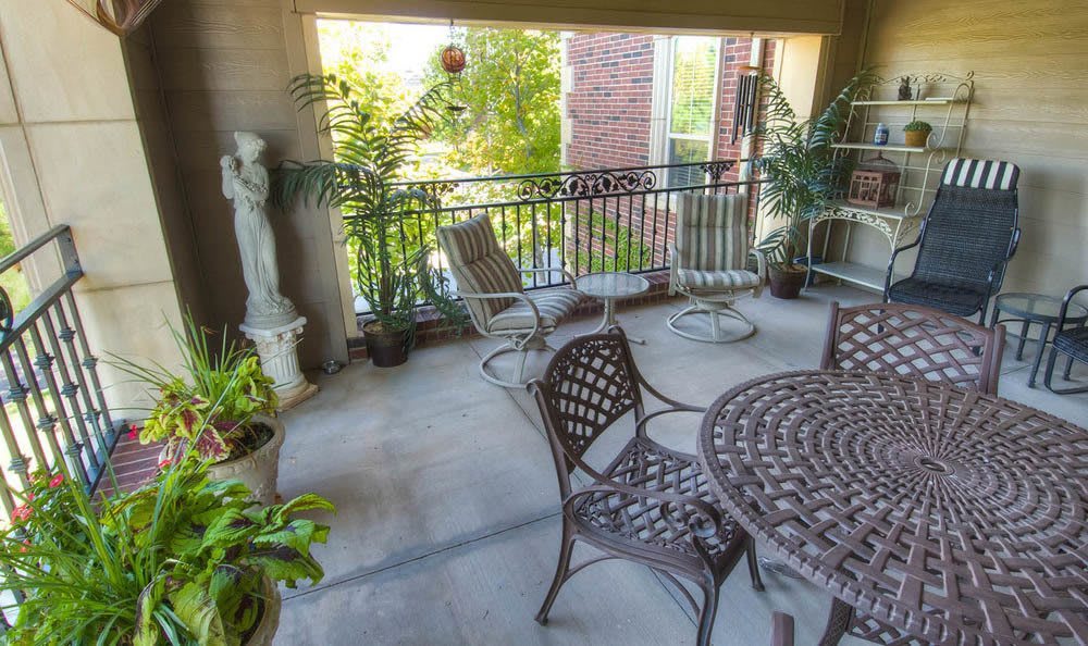 A cozy balcony adorned with patio furniture, lush plants, and a decorative statue.