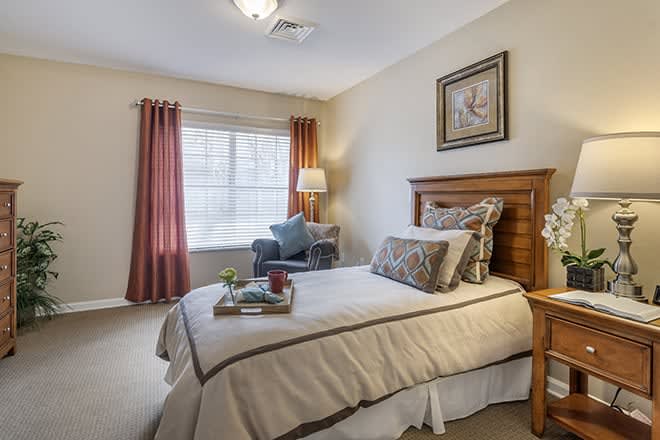A cozy bedroom with a single bed and wooden furniture, featuring soft lighting and elegant decor.