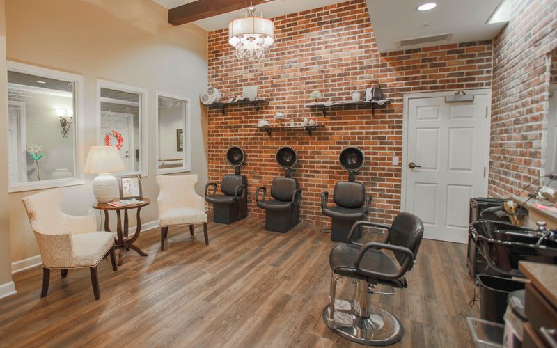 Modern salon interior with brick wall and hair drying stations.
