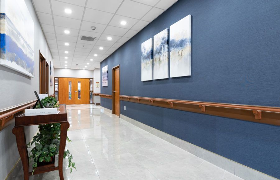 A well-lit hospital hallway with artwork on the walls and double doors at the end.
