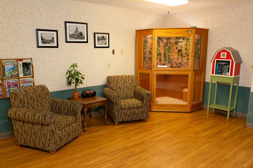 A cozy seating area featuring patterned chairs, a wooden cabinet, and framed photographs on the wall.