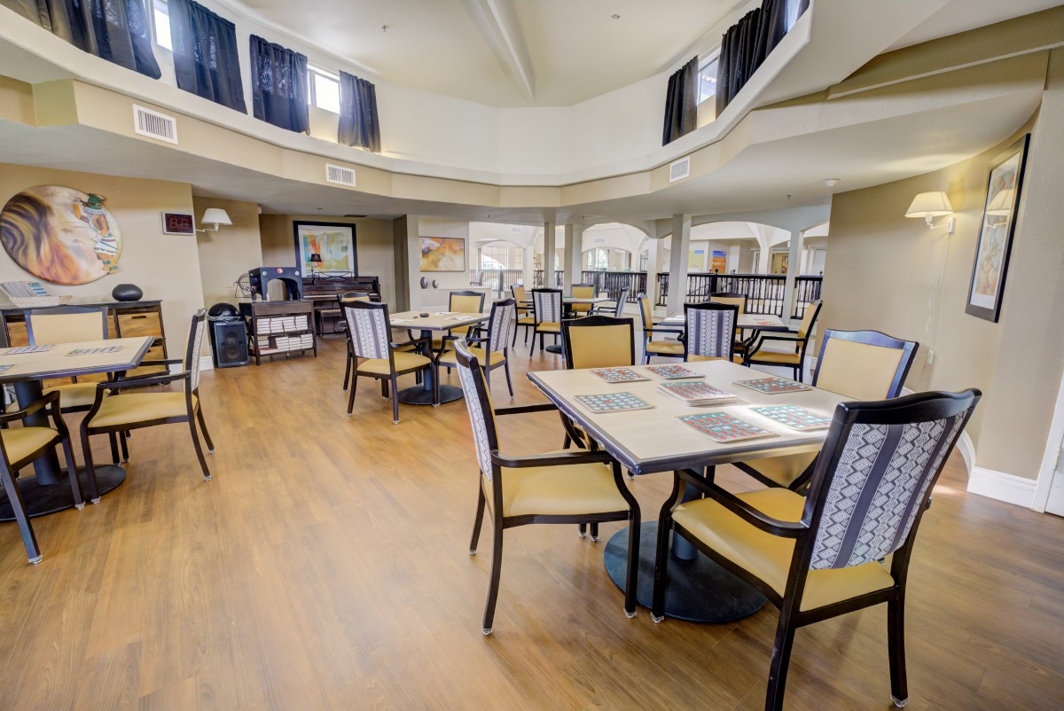 A spacious dining area with neatly arranged tables and chairs, featuring a modern interior design and wooden flooring.