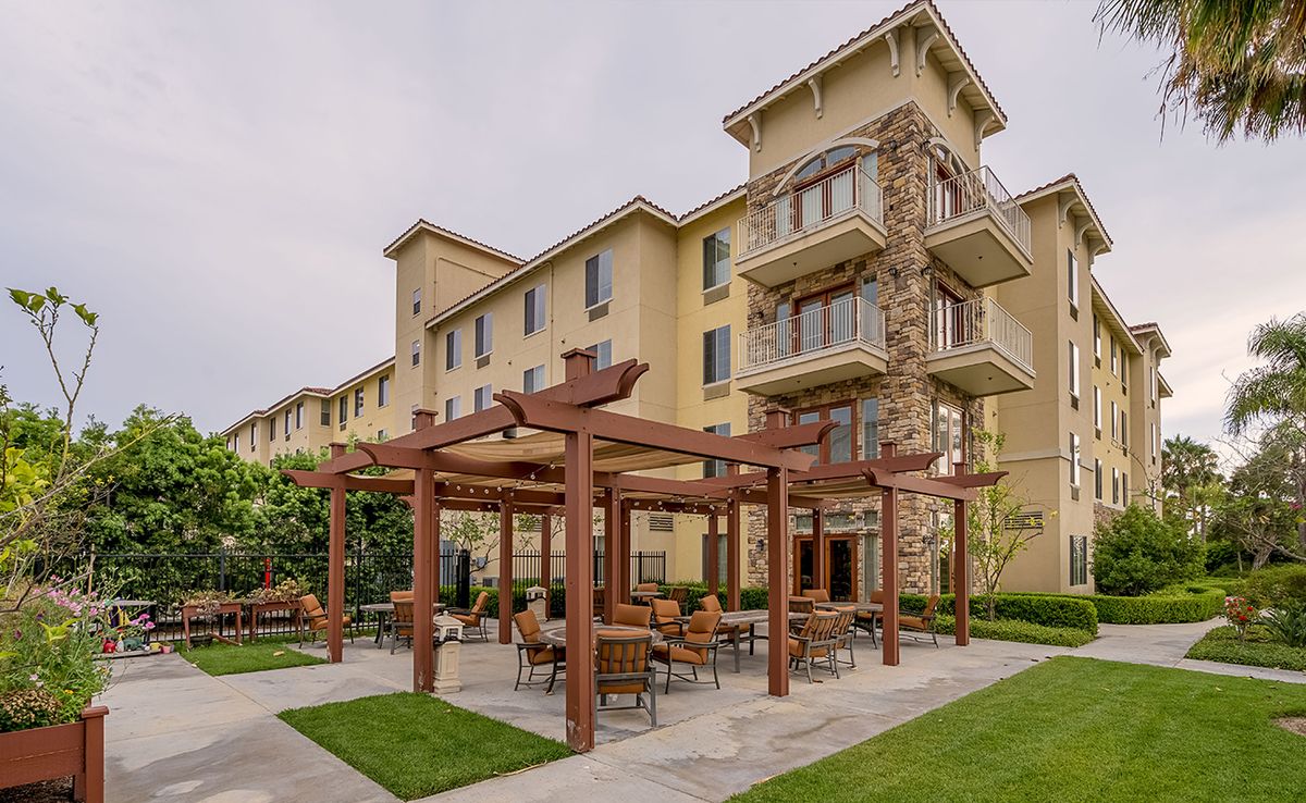 A residential apartment complex with an outdoor seating area under a pergola.