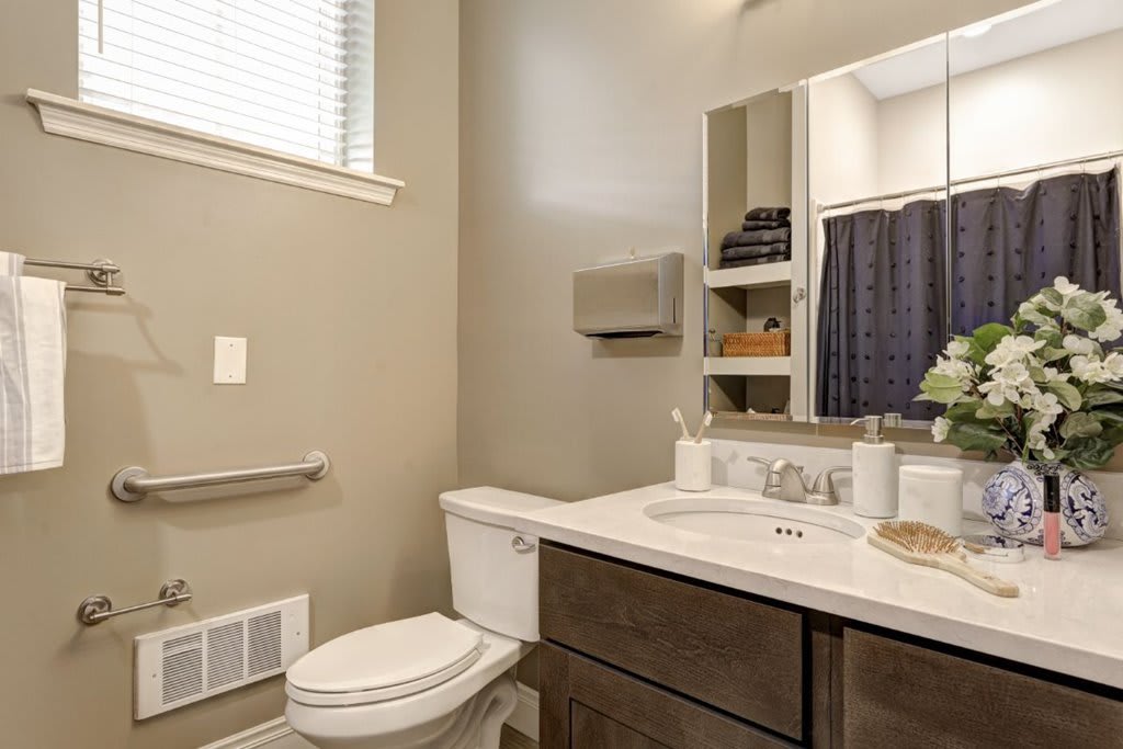A modern bathroom featuring a sink, mirror, and toilet with neatly arranged towels.