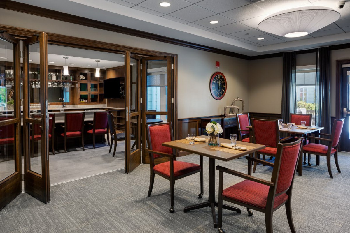 A cozy restaurant dining area with neatly arranged tables and chairs, featuring warm lighting and elegant decor.