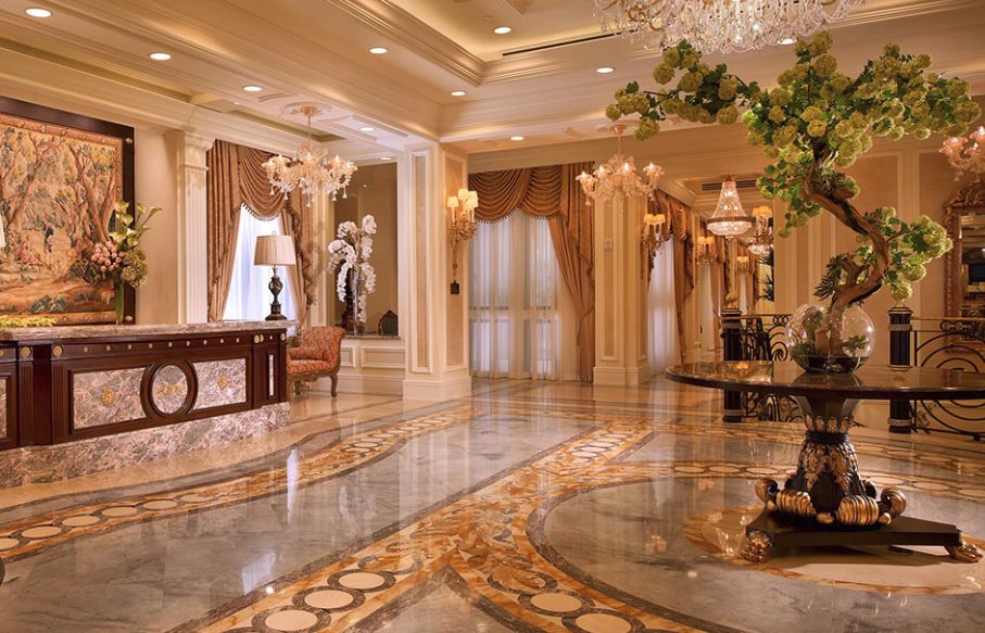 A luxurious hotel lobby with marble flooring and ornate chandeliers.