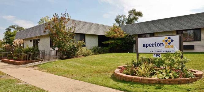 A single-story building with a sign outside, surrounded by grass and trees.