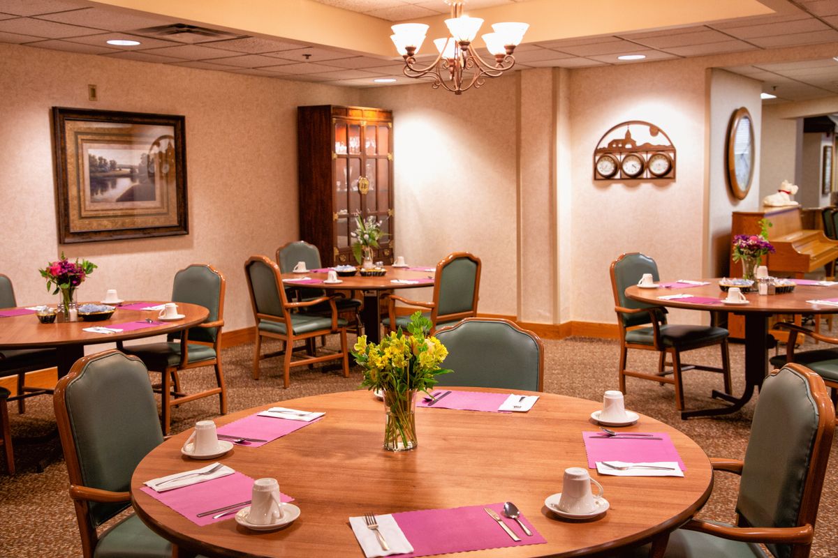 A well-arranged conference room with round tables, chairs, and a classic chandelier.