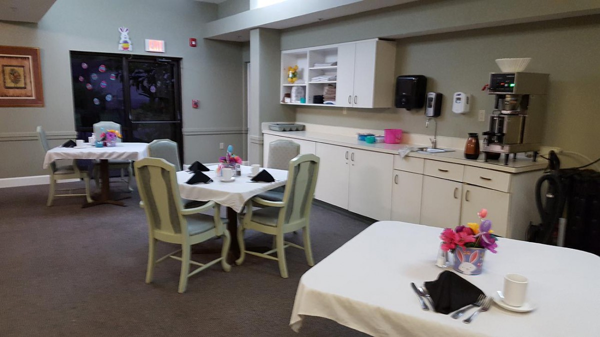 A cozy dining area with tables set, surrounded by a kitchenette.