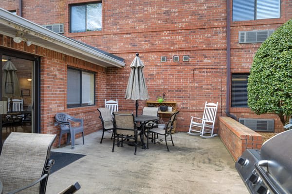 A cozy patio with a table, chairs, and an umbrella against a brick wall.