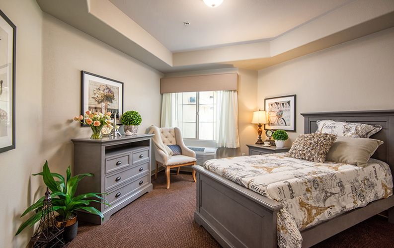 A cozy bedroom featuring elegant decor, a comfortable armchair by the window, and warm lighting.