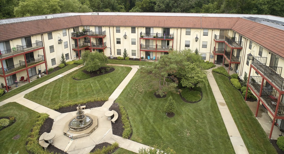 Aerial view of an apartment building with a landscaped courtyard and a central fountain.