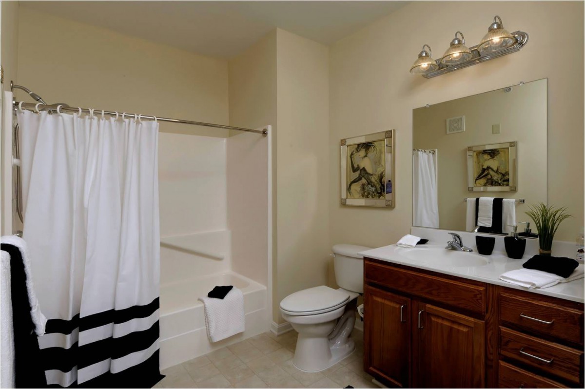 A modern bathroom featuring a bathtub with a shower curtain, a vanity with a mirror, and neatly arranged towels.