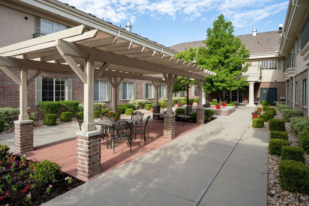 A spacious outdoor patio area with a pergola and seating arrangements in a well-maintained garden setting.