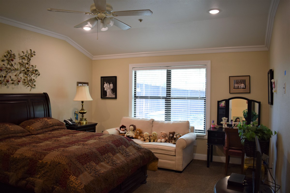 A cozy bedroom featuring a bed, sofa, and large window with natural light.