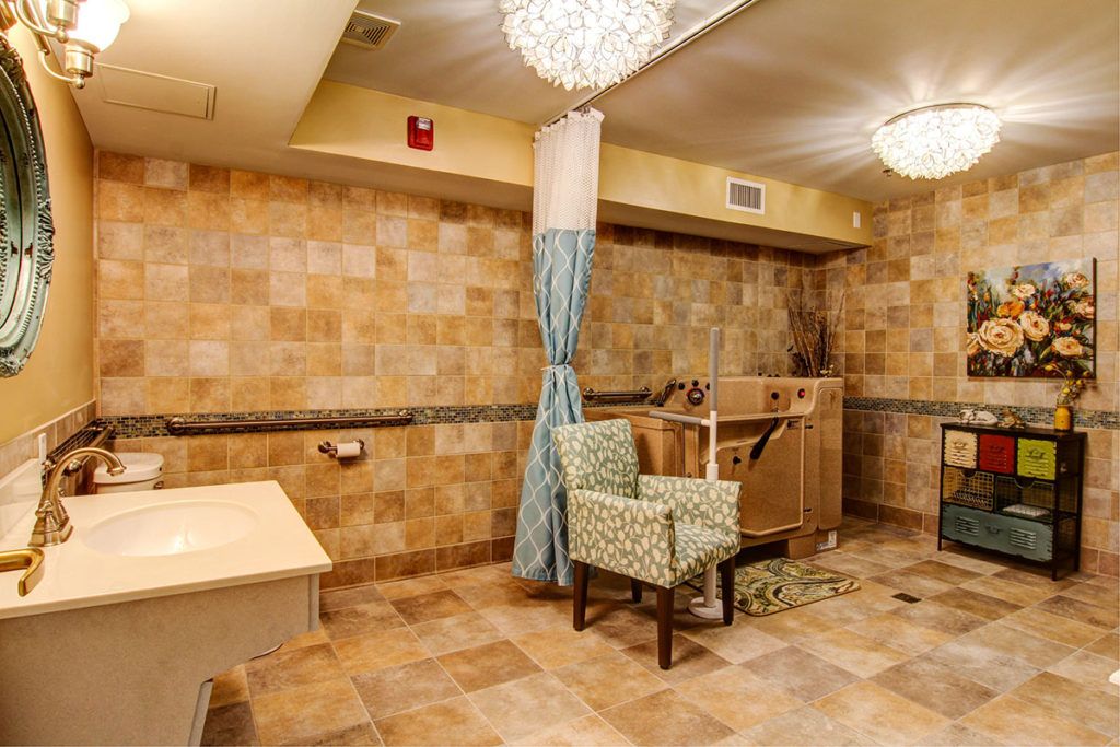 A well-lit interior room featuring tiled walls, a comfortable chair, and elegant light fixtures.