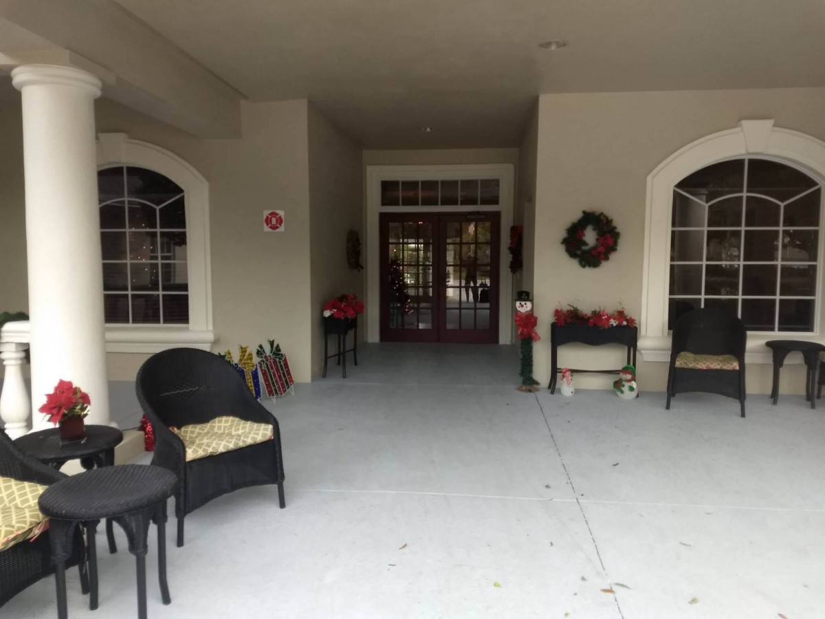 A welcoming porch entrance decorated with chairs, tables, and a wreath.
