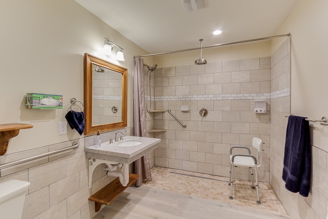 A spacious, accessible bathroom with grab bars and a walk-in shower.