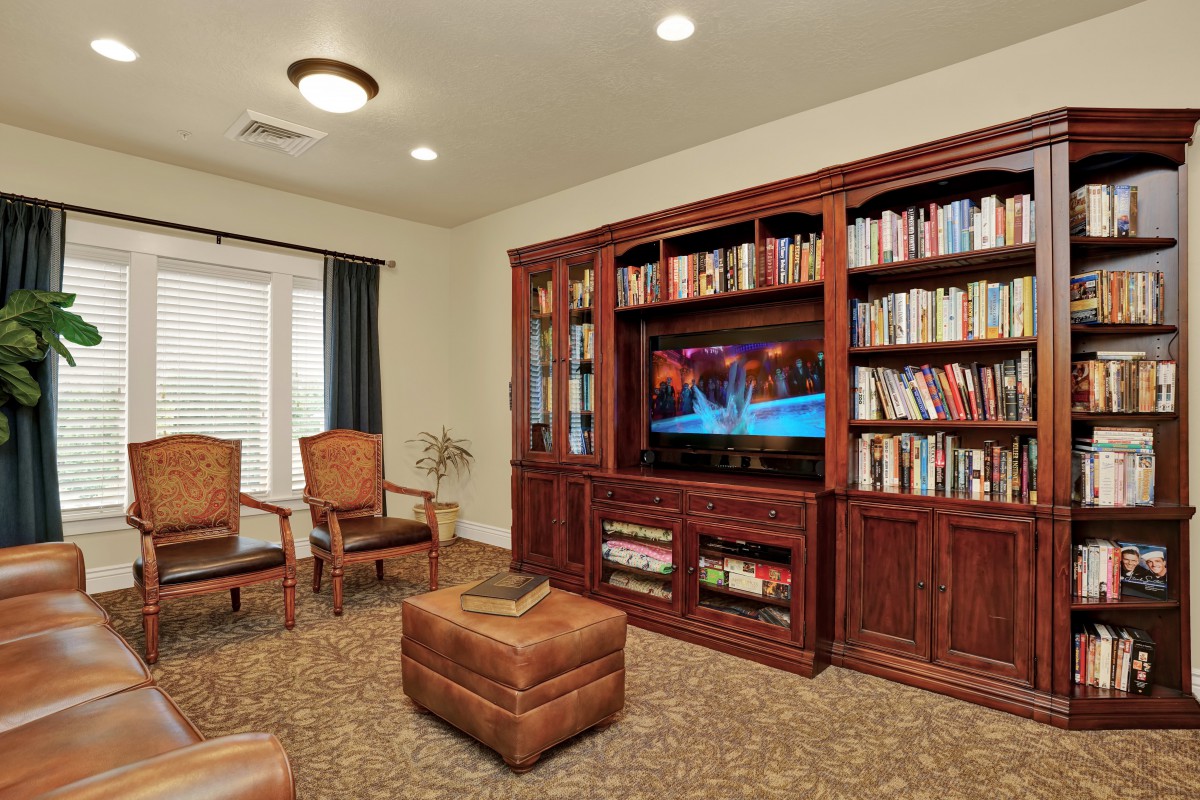 A cozy living room with a large wooden bookshelf, television, and comfortable seating.