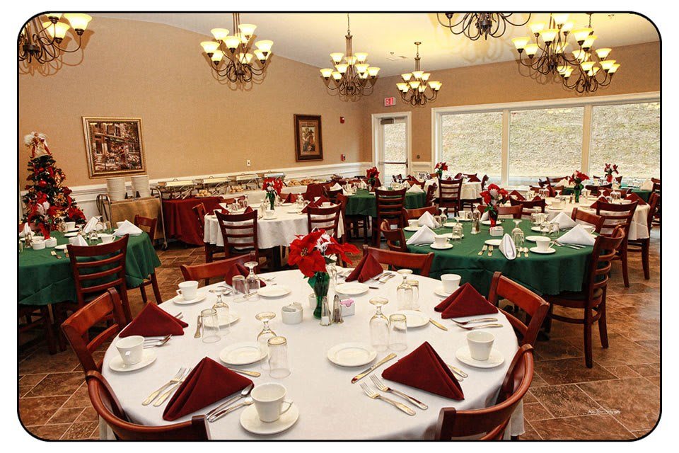 An elegant dining room set up with multiple tables, each adorned with white tablecloths and neatly arranged tableware.